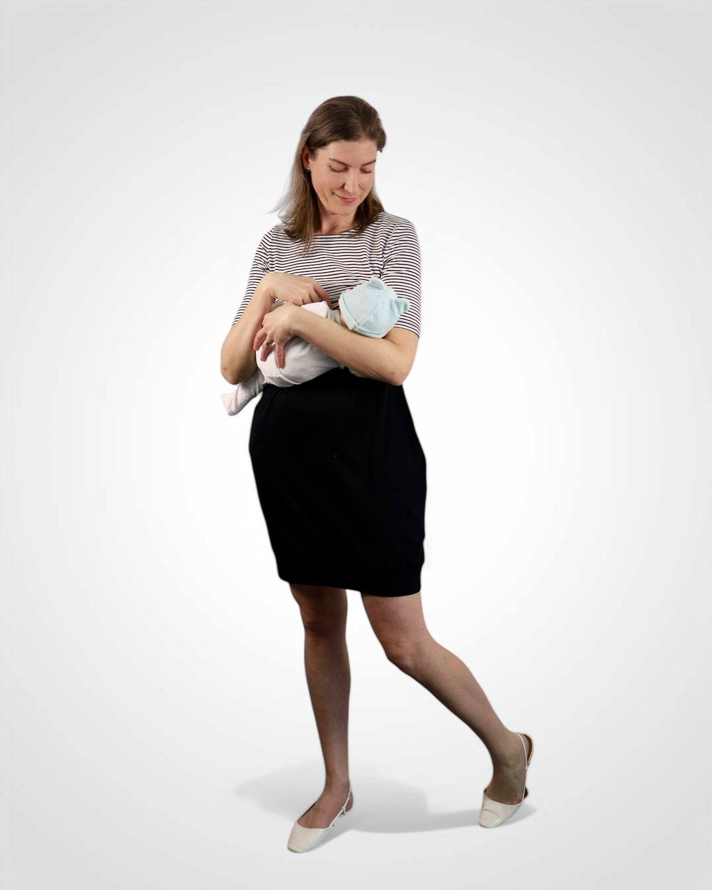 Mama dojčí bábätko v prúžkovaných kojo šatách s čiernou balónovou sukňou.