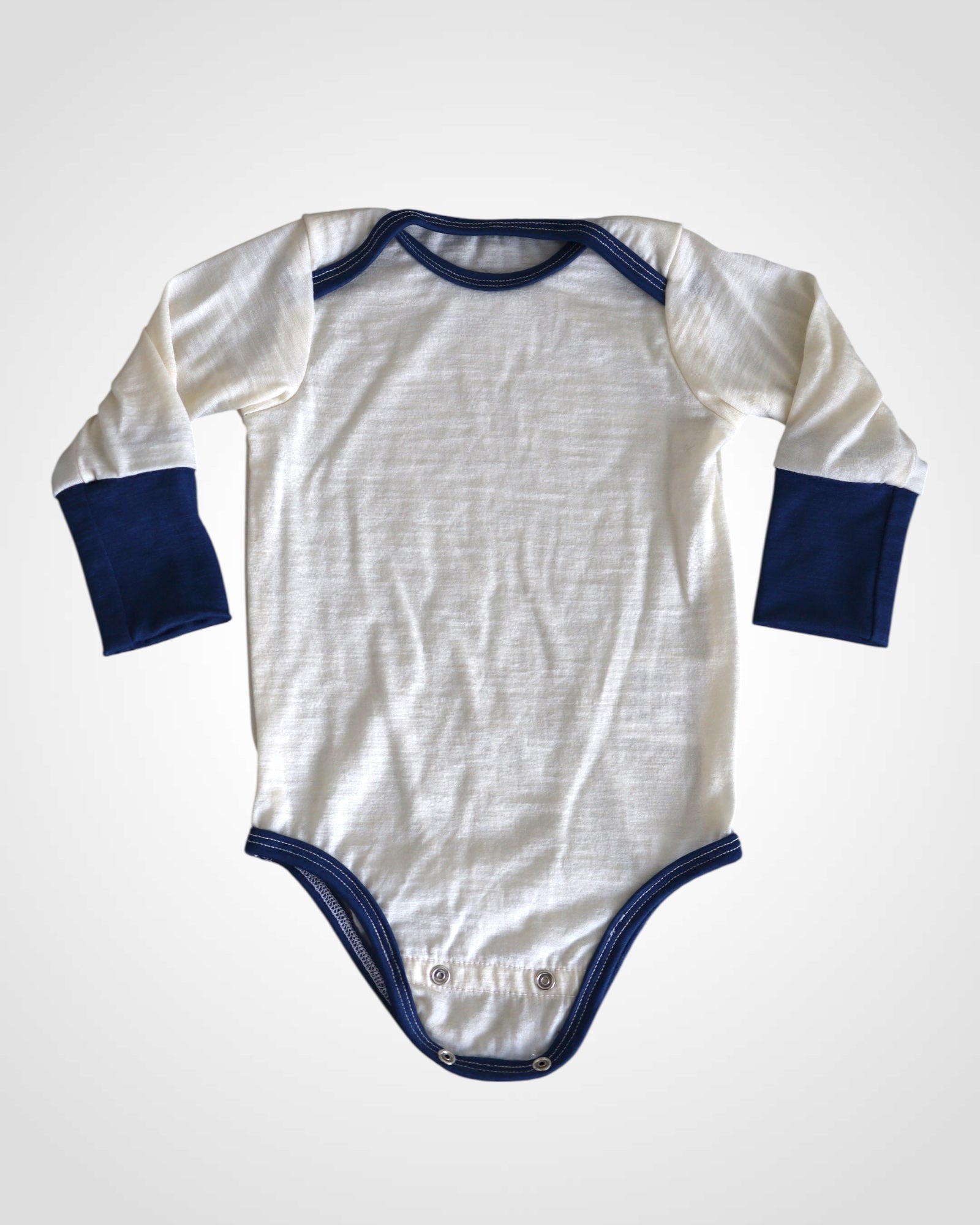 Detail nefarbeného 100% merino úpletu a modrý lem – radi ušijeme kombináciu podľa vášho výberu.