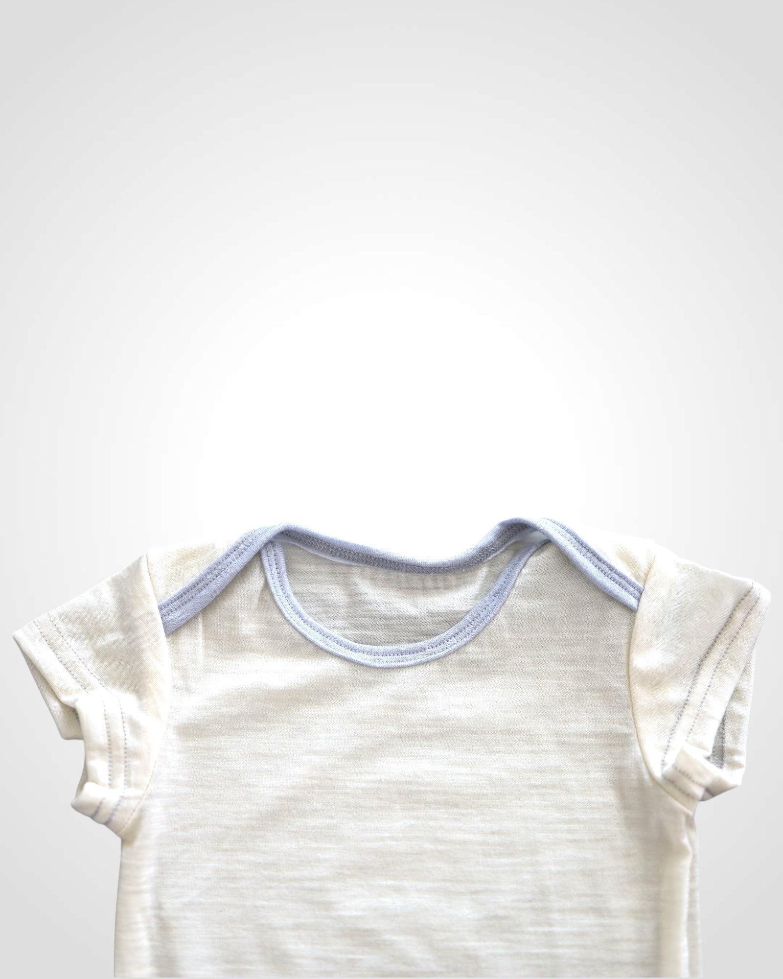 Detail nefarbeného 100% merino úpletu bez cvoku pri krku  – prírodné, jemné a hypoalergénne telo pre bábätká.