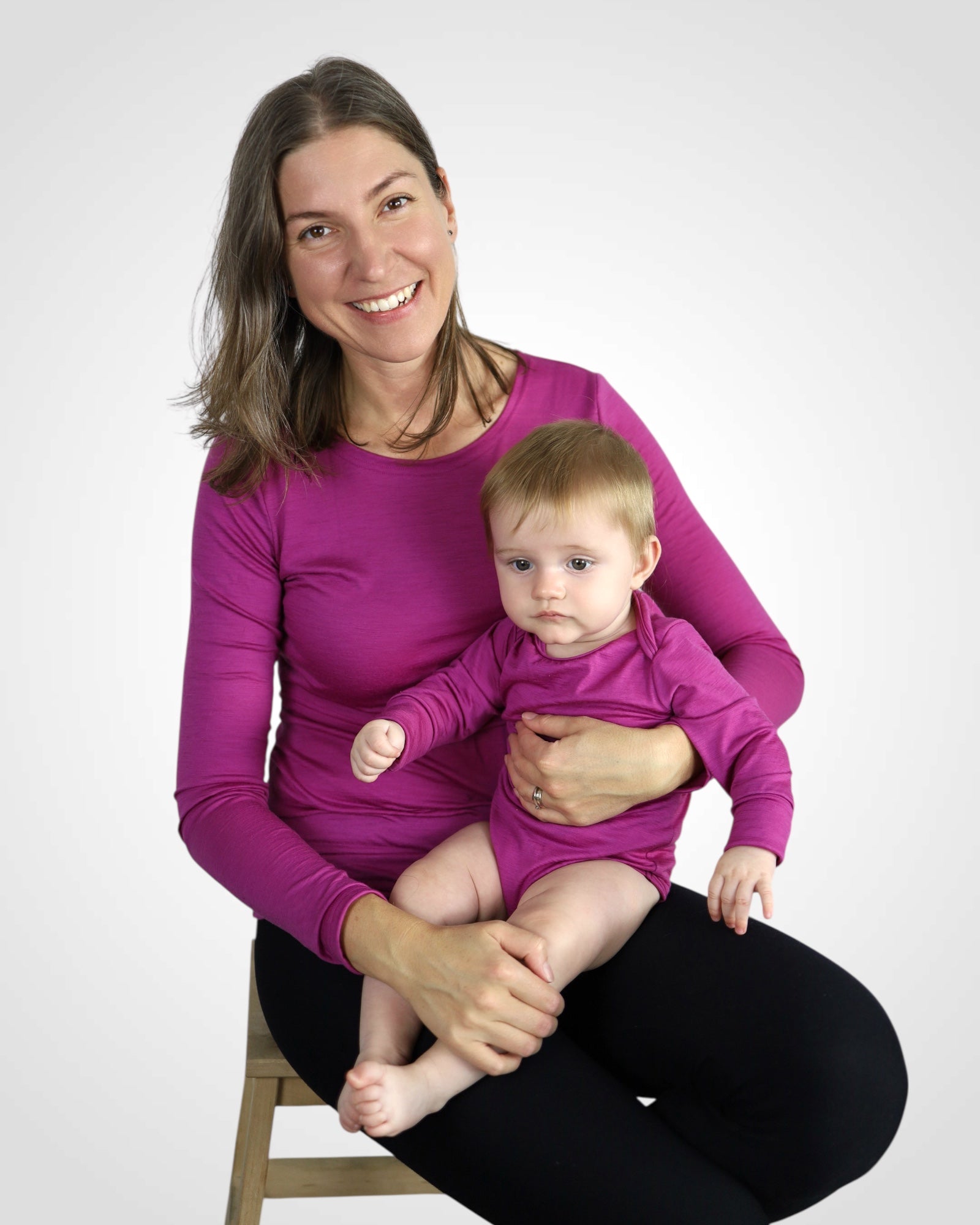 Mama v nosiacom merino tričku a bábätko v rovnakom cyklaménovom body, ideálne zladenie pre každodenné pohodlie.